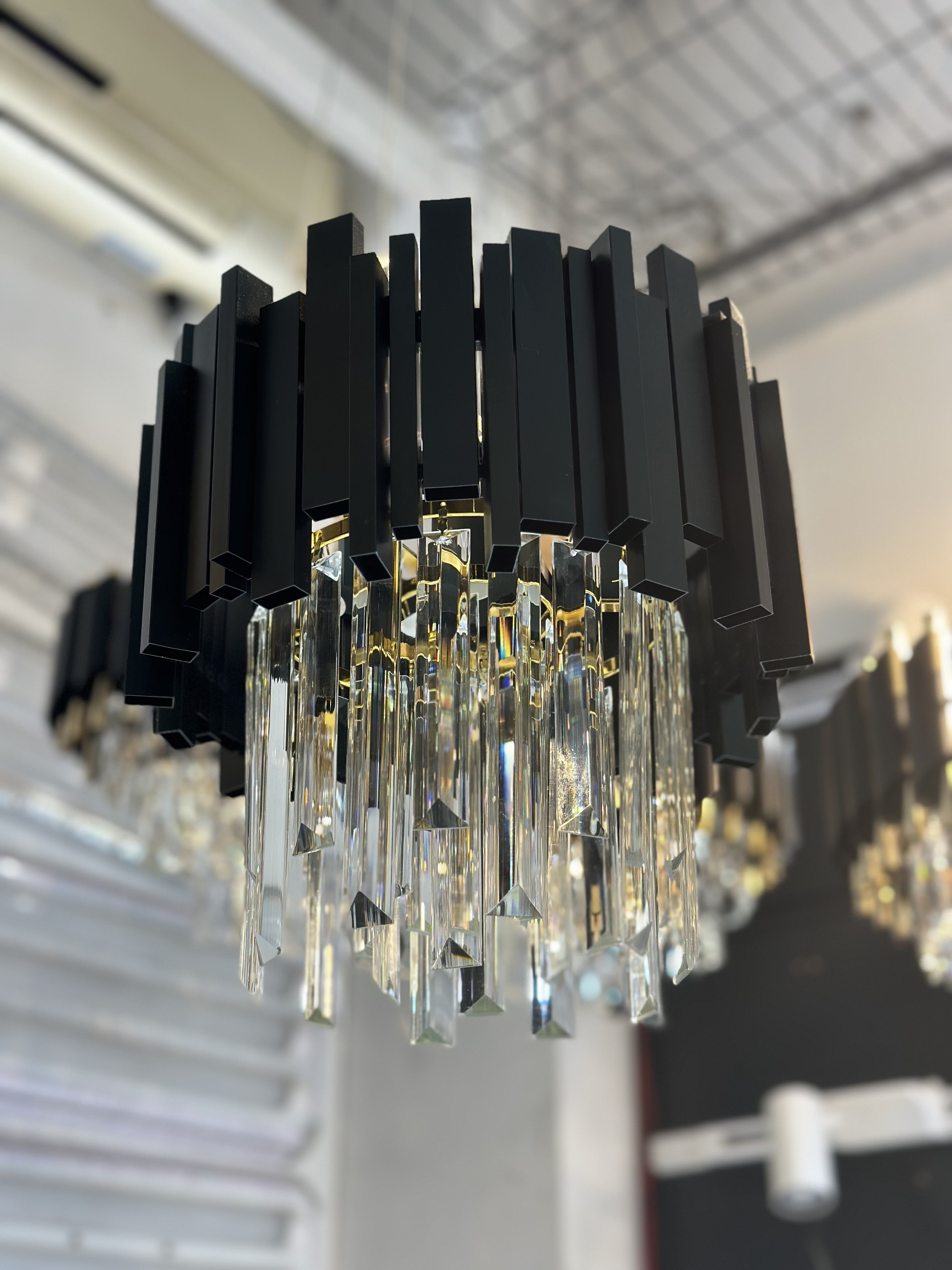 Candelabru cristal cu cadru negru mat si cristale transparente suspendate, montat in showroom, vedere de aproape