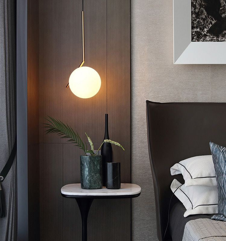 Lustra pendul glob sticla montata deasupra noptierei intr-un dormitor modern, lumina calda difuza