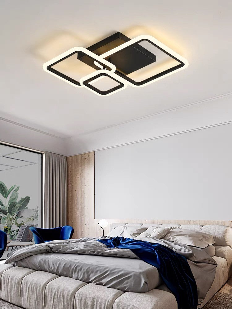 Lustra LED de plafon cu 3 cadre patrate negre montata in dormitor modern, lumina calda ambientala