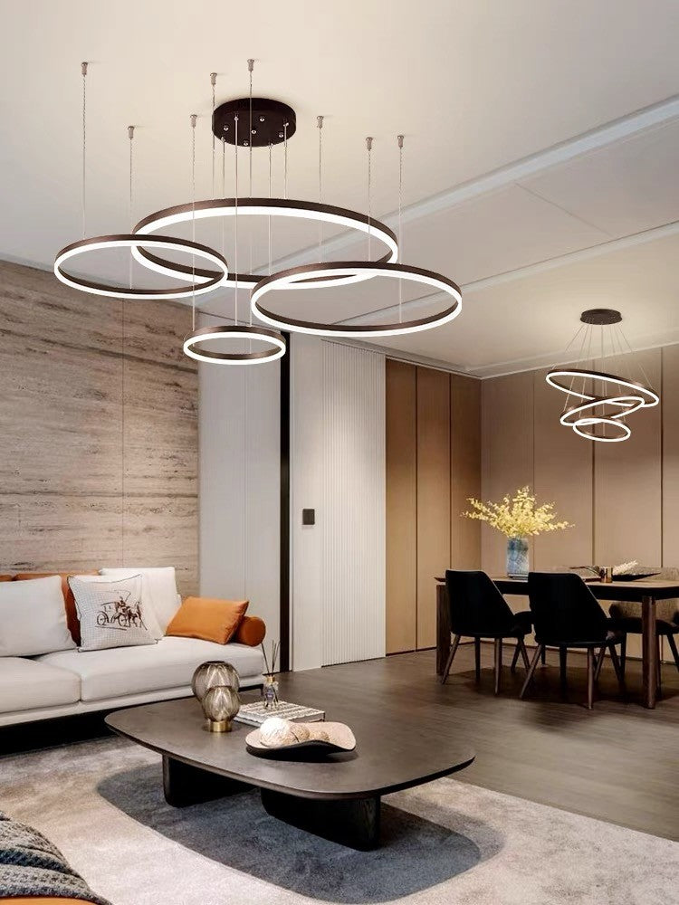 Candelabru LED cu inele circulare maro, reglabil, instalat in open-space cu zona de dining