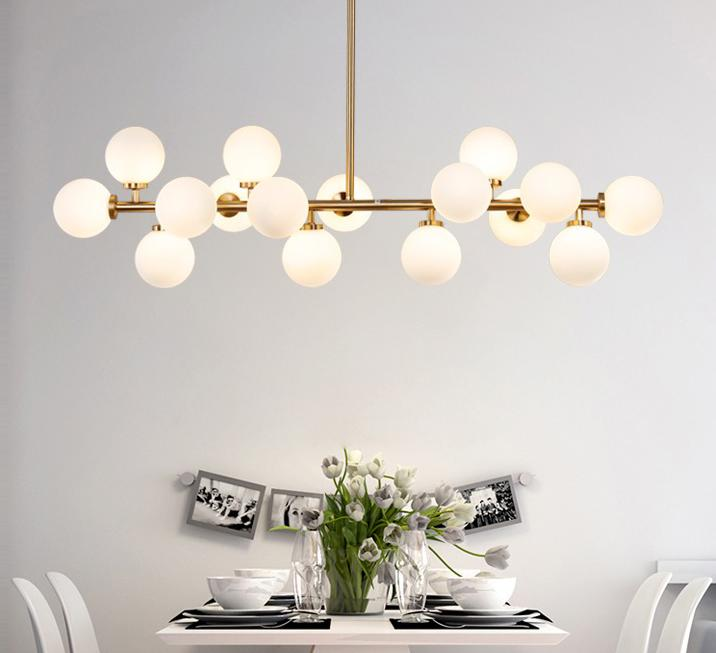 Lustra liniara aurie cu globuri mate deasupra mesei de dining, aspect modern