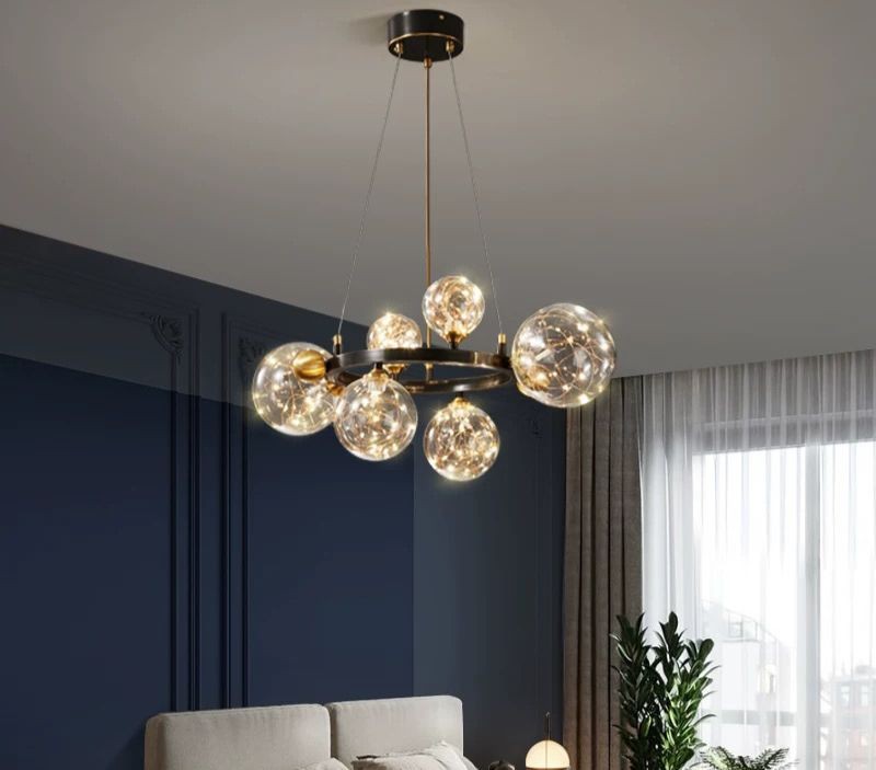 Lustra cu sfere de sticla transparente si micro-LED-uri tip licurici, suspendata in living cu perete albastru